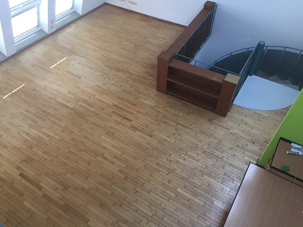 Heller Raum mit Holzfußboden, Treppe und einem grünen Wandanstrich.