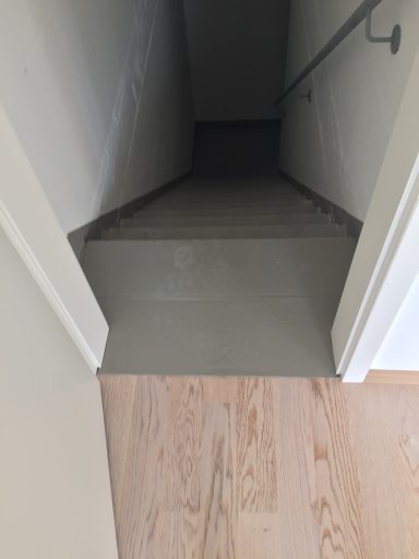 Blick auf eine Treppe, die in einen dunklen Bereich führt, mit hellem Fußboden.