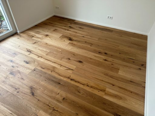 Holzboden in einem hellen Raum mit großen Fugen und natürlicher Maserung.