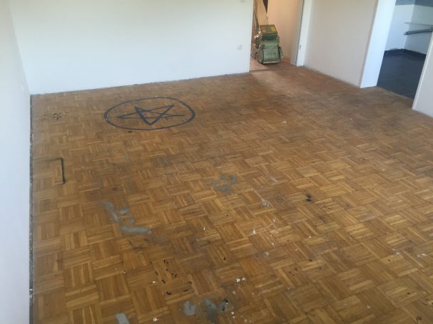 Holzboden mit sichtbaren Abnutzungsspuren und einem Symbol in der Mitte.