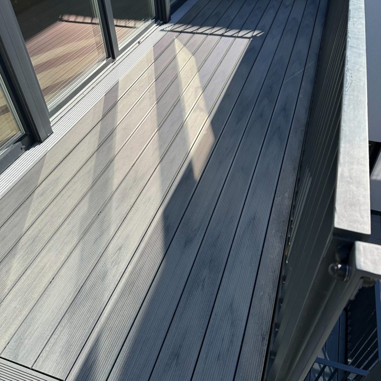 Holzboden auf einem Balkon mit Sonnenlichtern und Schatten.