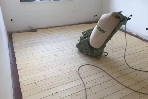 Maschine zum Abschleifen eines Holzbodens in einem leerstehenden Raum.