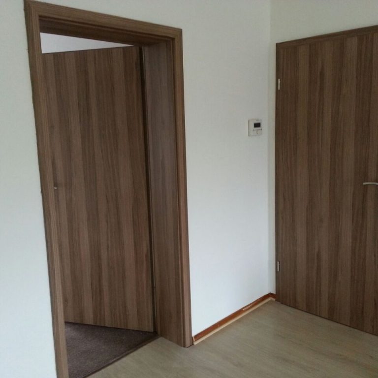 Holzgetäfelte Tür und Wand in einem Raum mit neutralen Farbtönen.