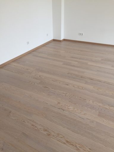 Holzboden in einem hellen Raum mit weißen Wänden, minimalistischem Design.
