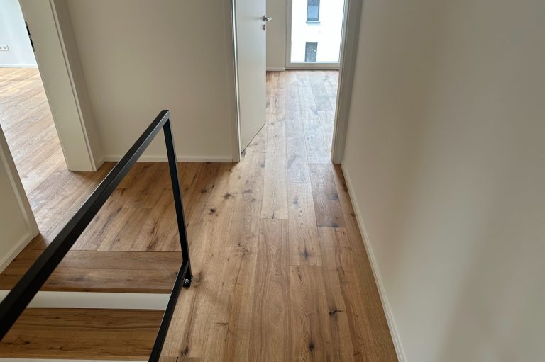 Holzboden in einem modernen Flur mit Treppe und natürlichem Licht.