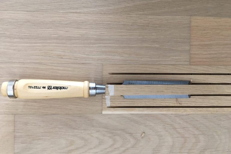 Holzwerkzeug mit Holzgriff und schlanker Klinge auf einer Holzoberfläche.