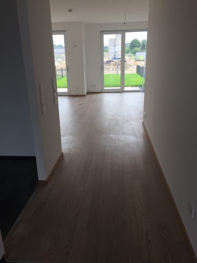 Heller Flur mit Holzfußboden und Blick auf Garten durch große Fenster.