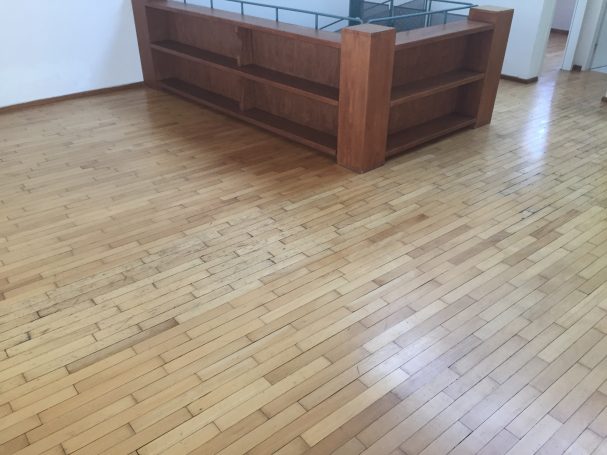 Holzboden mit einem niedrigen, holzfarbenen Regal im Hintergrund.