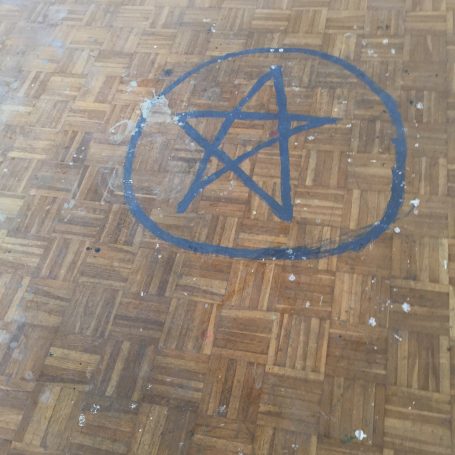 Holzboden mit blauer Pentagramm-Zeichnung im Kreis.