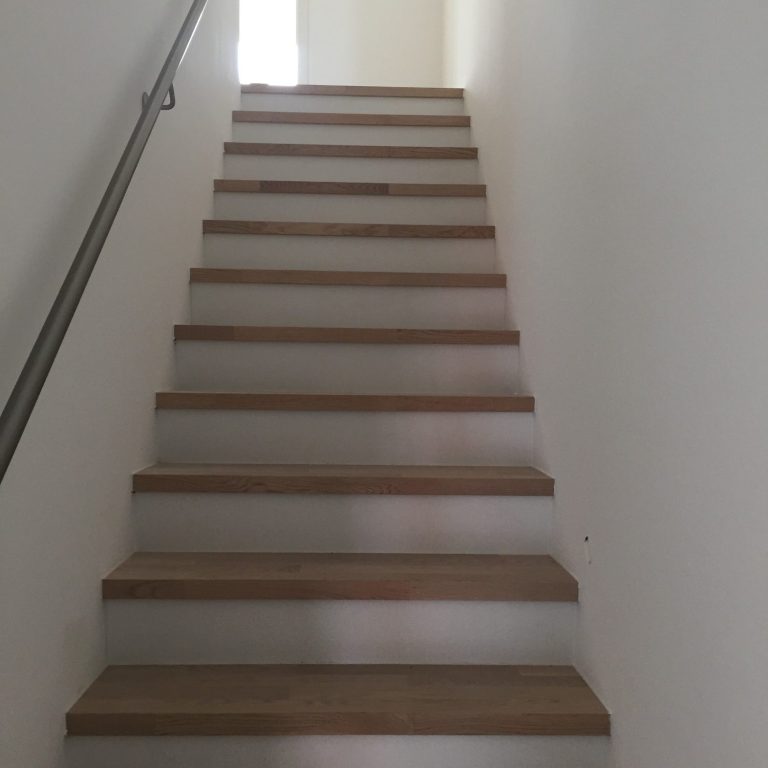 Stufen mit Parkett verlegt Treppenhaus mit Holzstufen und einer weißen Wand im Hintergrund.