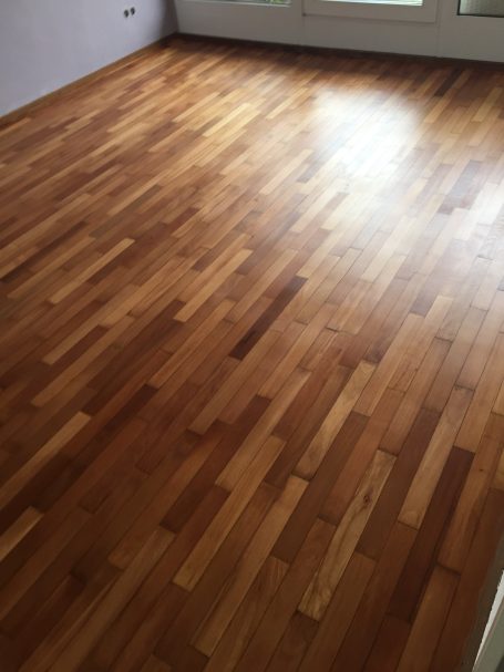 Holzboden in warmen Farbtönen, gleichmäßige Verlegung, heller Raum.